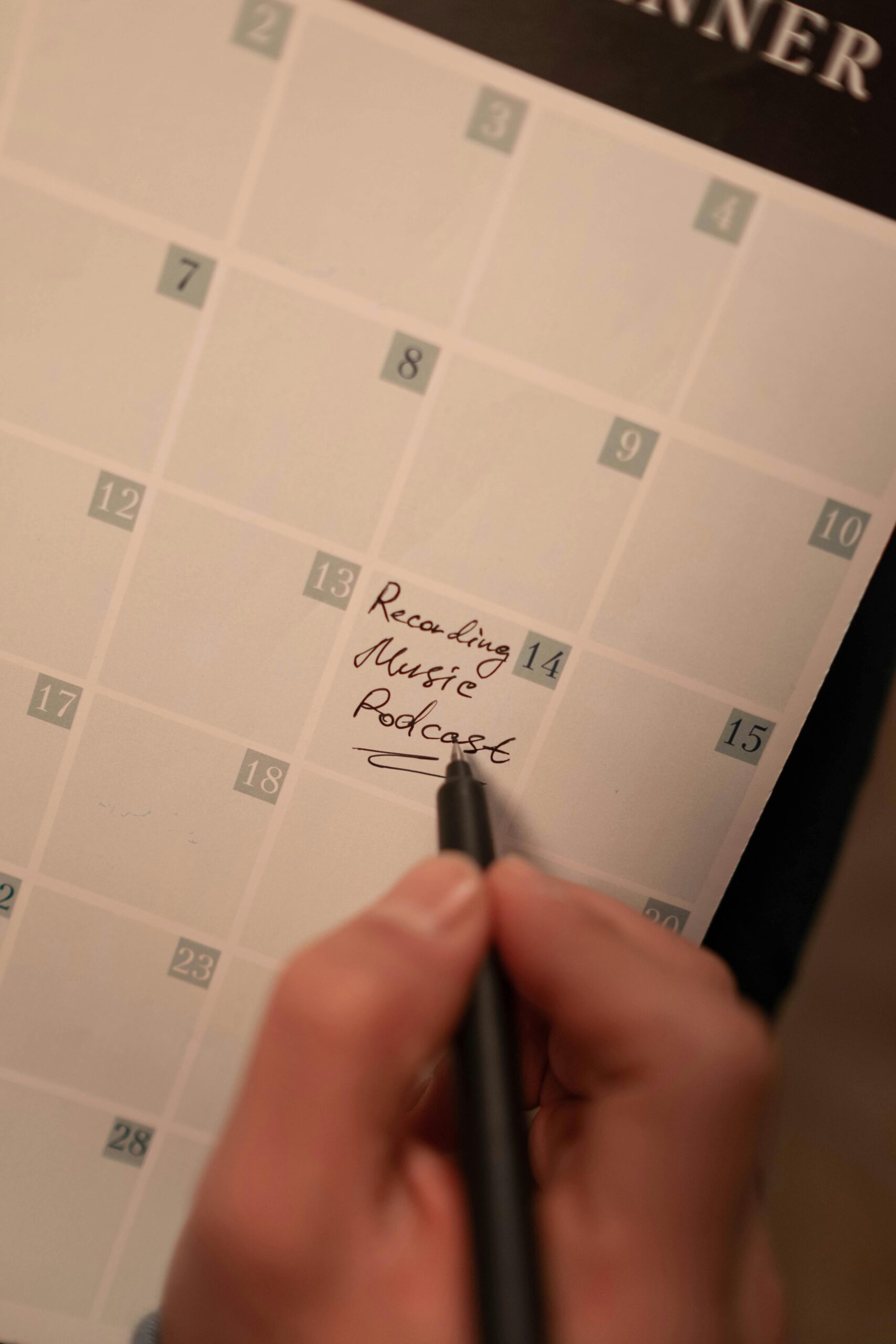 Close-up of a hand writing podcast recording date on a calendar. Ideal for content planning concepts.